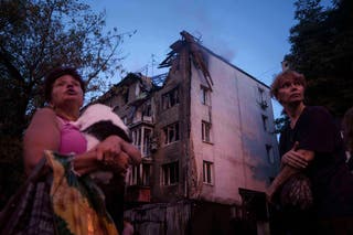 Local residents stand outside of their house which was heavily damaged by a Russian strike in Kyiv
